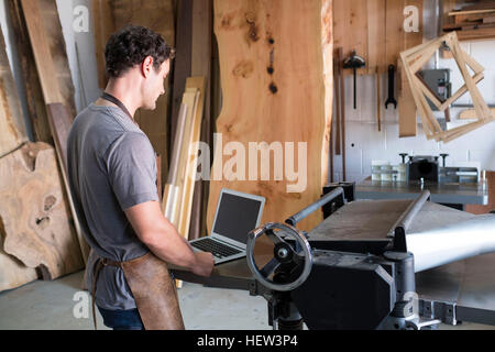 Carpenter at his workshop, using laptop Stock Photo