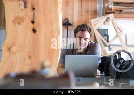 Carpenter at his workshop, using laptop Stock Photo