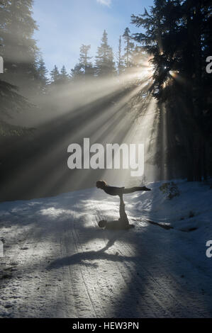 Silhouettes of acrobats in snow covered forest balancing, Frog lake, Mount Hood, Oregon, USA Stock Photo