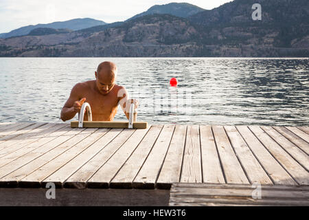 Man climbing ladder onto pier, Penticton, Canada Stock Photo