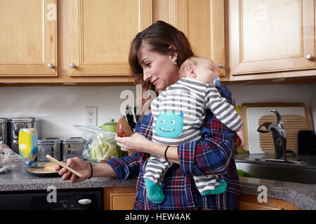 Mother holding sleeping baby boy and looking at smartphone Stock Photo