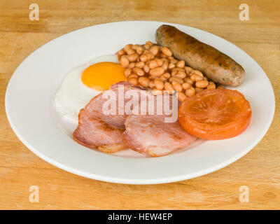 Full English Breakfast Bacon Egg Sausage Baked Beans and Tomato Served on a White Plate Stock Photo