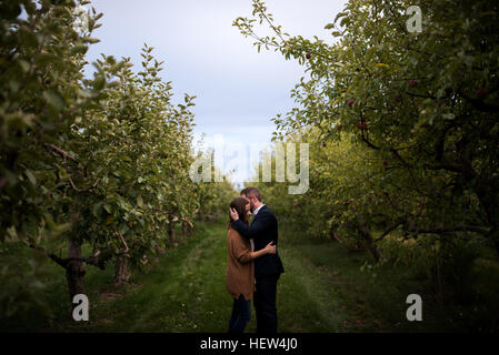 Romantic mid adult couple embracing in orchard Stock Photo