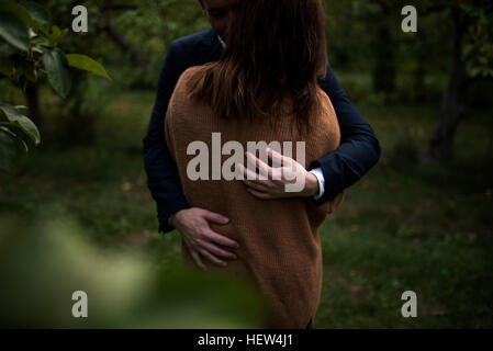 Mid section of romantic couple hugging in orchard at dusk Stock Photo