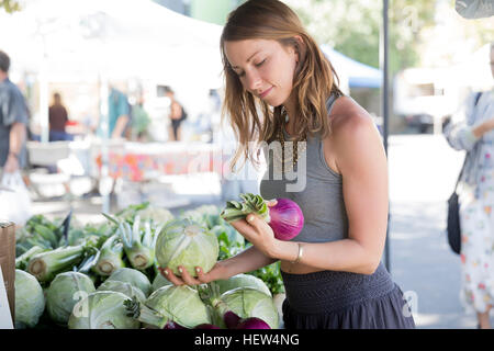 Woman at fruit and vegetable stall selecting red onions Stock Photo