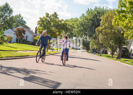 Romantic senior couple holding hands cycling along suburban road Stock Photo