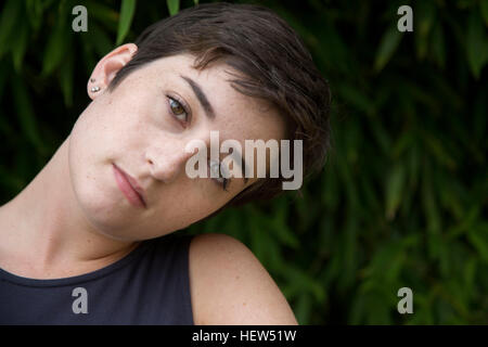 Portrait of young woman with cropped hair, outdoors, pensive expression Stock Photo