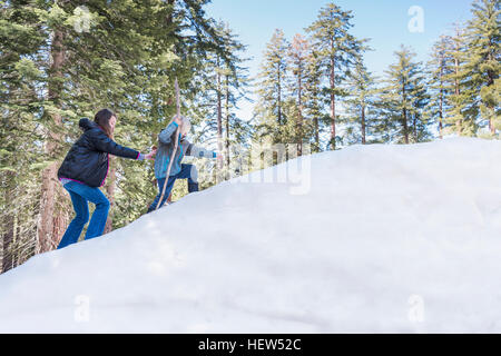 Two children walking up snowy hill, Sequoia National Park, California, USA Stock Photo