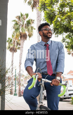 Young man riding bicycle, smiling Stock Photo