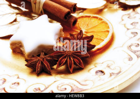 Christmas platter decorated with bound cinnamon sticks, a biscuit, a dried orange slice and dried star anise Stock Photo