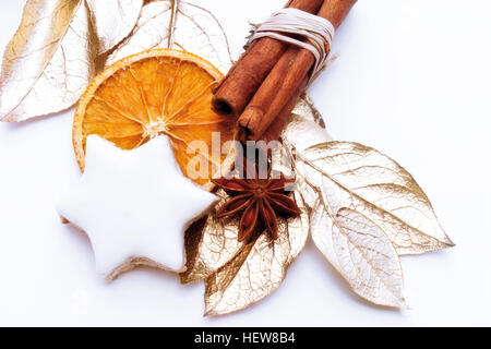 Star anise, bound cinnamon sticks, a biscuit, and gold painted dried bay leaves, Christmas decoration Stock Photo