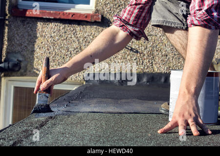 A man reseals an exterior home roof DIY. Stock Photo