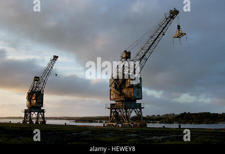 A photograph of derelict wharf cranes in Greymouth, New Zealand, highlighting the region's industrial past. The cranes, now abandoned, stand as remnants of the city's once-thriving dock and harbor operations. Stock Photo