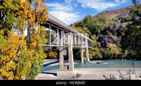 Situated 10 kilometres from Queenstown (off highway 6), the Old Lower Shotover Bridge was built in 1871 and offers foot traffic eye-catching 360 panoramic views of the Shotover River.  The original bridge was washed away in 1878 by flooding but rebuilt by the Public Works Department and re-opened in 1915. The bridge is172 metres long and stands16 metres from bridge to the river below.  Foot traffic can enjoy panoramic views of the Shotover River and surrounding mountains including the Remarkables Double Cone Peak (2319m), Cecil Peak (1978m), Coronet Peak (1651m) and Brow Peak (1456m).  The bri Stock Photo