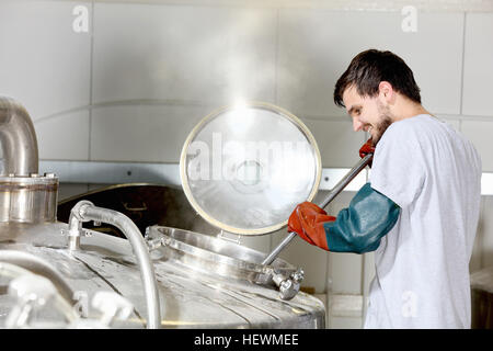Worker in brewery, adding hops to brew kettle Stock Photo