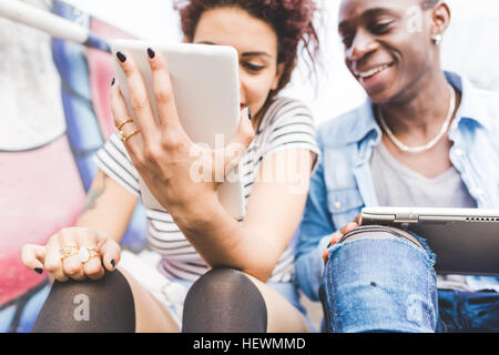 Couple using digital tablets smiling Stock Photo