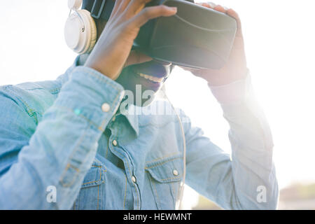Man wearing virtual reality and headphones smiling Stock Photo
