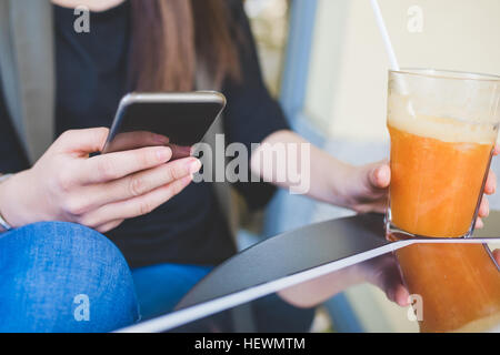 Cropped shot of young woman using smartphone at sidewalk cafe Stock Photo