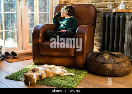 Boy relaxing on arm chair after school Stock Photo