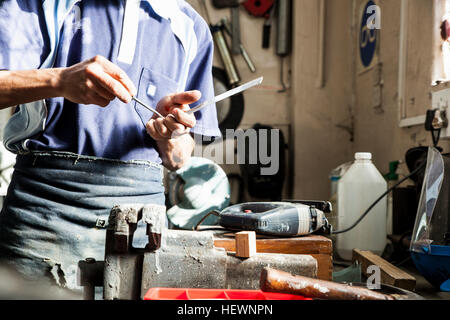 Mid section of young man using screwdriver in repair workshop Stock Photo