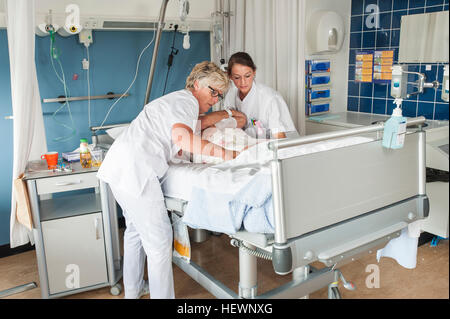 Nurses tending to patient in hospital bed Stock Photo - Alamy