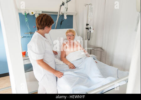 Nurse tending to patient in hospital bed wearing oxygen mask Stock ...