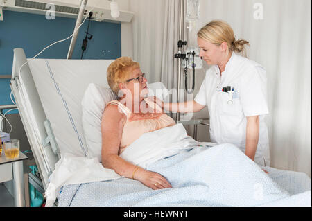 Nurse tending to patient in hospital bed wearing oxygen mask Stock ...