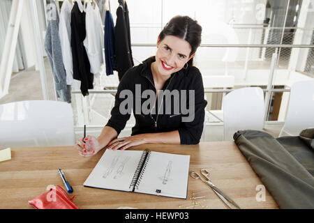 Woman sketching fashion design, looking at camera smiling Stock Photo