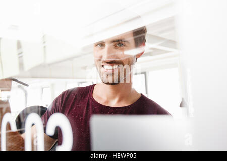 Portrait of man looking through glass at camera, smiling Stock Photo