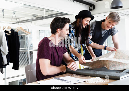 Colleagues at desk looking at folding map smiling Stock Photo