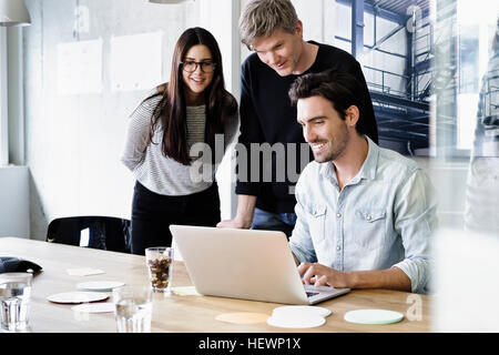 Colleagues in office using laptop smiling Stock Photo