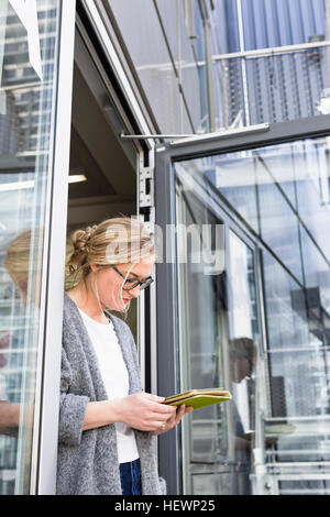 Woman in doorway using digital tablet Stock Photo