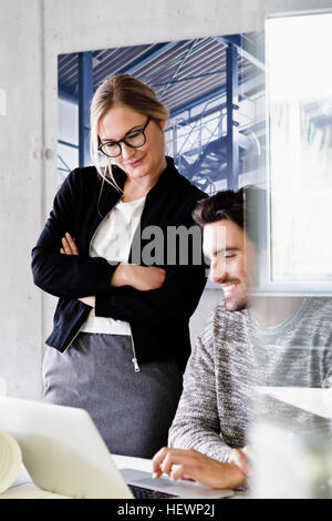 Colleagues in office using laptop smiling Stock Photo