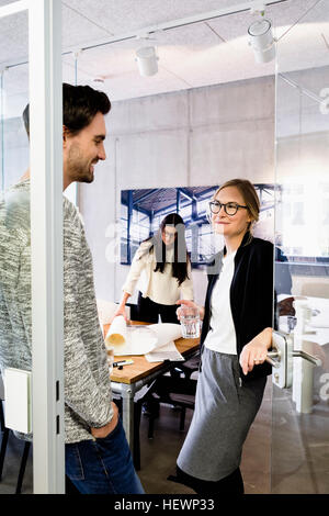 Colleagues in office doorway chatting Stock Photo