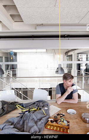 Fashion designer at table holding tea cup looking away Stock Photo