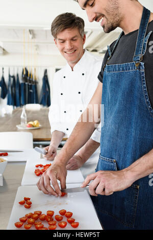 Chefs in kitchen slicing tomatoes Stock Photo
