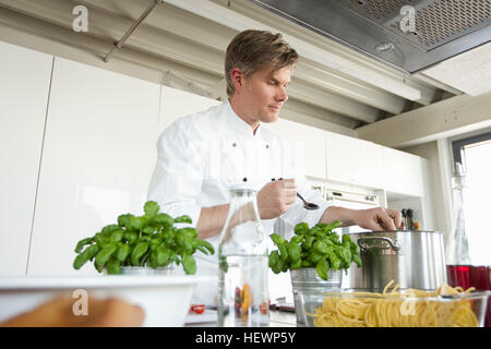 Chef in commercial kitchen cooking Stock Photo