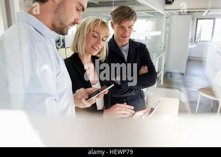 Colleagues in office looking at smartphone Stock Photo