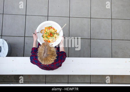 Overhead view of woman holding serving bowl of pasta Stock Photo