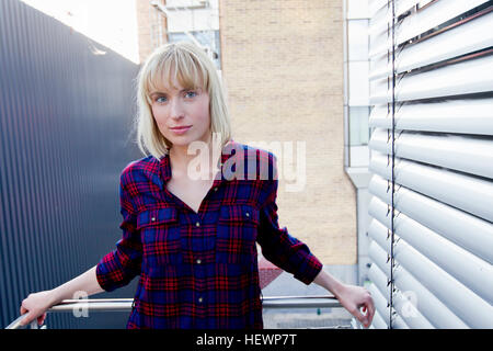 Portrait of blonde haired woman on balcony looking at camera Stock Photo