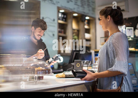 Barista calculating bill for female customer at cafe counter Stock Photo