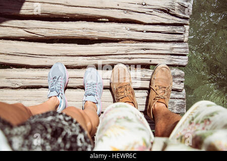 Personal perspective of couples feet standing on wooden bridge, Plitvice Lakes National Park, Croatia Stock Photo