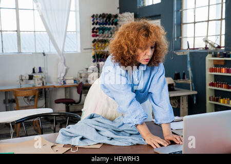 Dressmaker in workshop using laptop Stock Photo