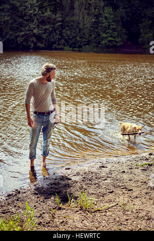 Mid adult man playing with dog in river Stock Photo