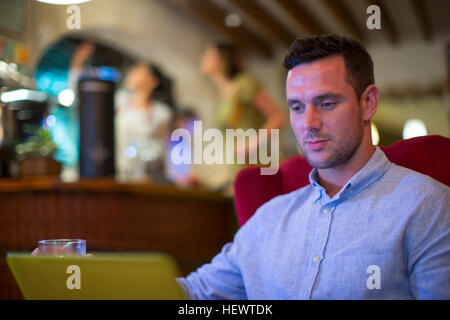 Man using laptop in restaurant Stock Photo