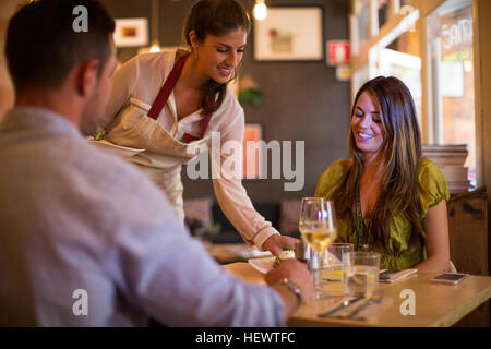 Waitress serving customers in restaurant Stock Photo