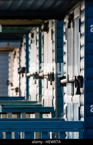 Dawn. View along beach hut doors locked with iron bar across them. High contrast pattern, side-lit, selective focus. Stock Photo