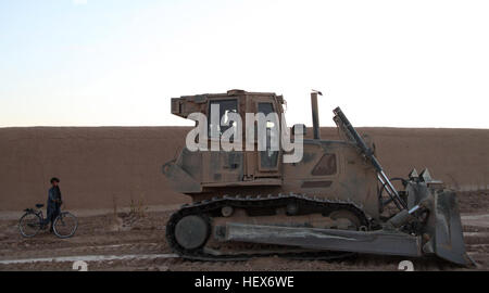 MUSA QALEH, Helmand province, Islamic Republic of Afghanistan – An Afghan boy stops behind a bulldozer operated by Lance Cpl. Robert Nickum, 24, a heavy equipment operator from Colorado Springs, Col., at a small combat outpost in Musa Qaleh, Nov. 3, 2010. Engineers with 1st Combat Engineer Battalion, 1st Marine Division (Forward), used the bulldozer to push large amounts of dirt into piles creating a large burm that encircled the position manned by 1st Battalion, 8th Marine Regiment. (U.S. Marine Corps photo by Cpl. John M. McCall) Engineers improve 1-8's defense in Musa Qal'eh DVIDS338911 Stock Photo