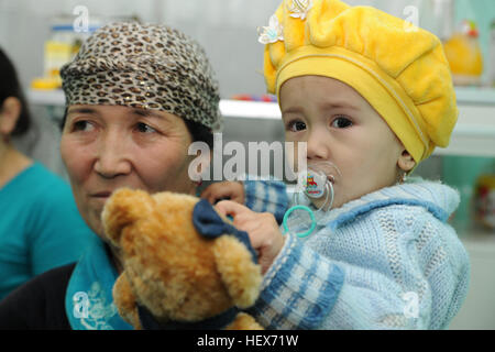 A child, patient at the Children's Cancer Center in Bishkek, is held in her mother's arms while she plays with her new bear received from members of the Transit Center at Manas Nov. 13. Members from the Transit Center at Manas visited the children as part of a team to assess the needs of the facility. (Photo by: Staff Sgt. Nathan Bevier) Flickr - DVIDSHUB - Transit Center visits Children's Cancer Center and retirement home in Bishkek (Image 1 of 6) Stock Photo