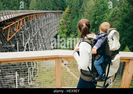 Young woman carrying son on back, rear view, Kinsol Trestle Bridge, British Columbia, Canada Stock Photo